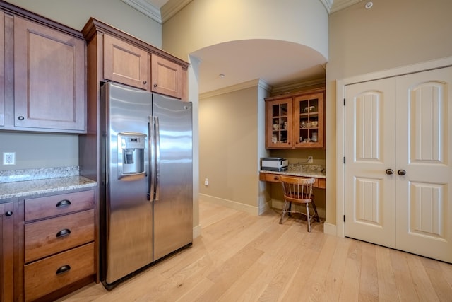 kitchen featuring crown molding, light wood-type flooring, built in study area, and stainless steel fridge with ice dispenser