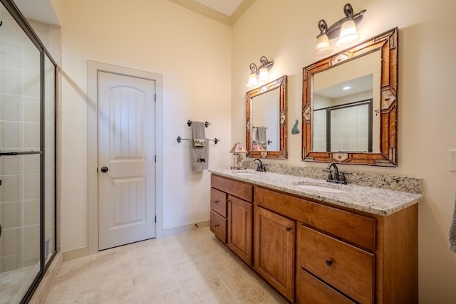 full bathroom featuring double vanity, a stall shower, a sink, and crown molding