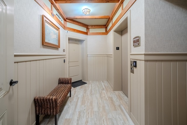 mudroom with a wainscoted wall, elevator, and light wood-style floors