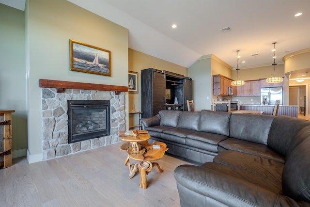 living area featuring lofted ceiling, a stone fireplace, light wood-style flooring, recessed lighting, and visible vents