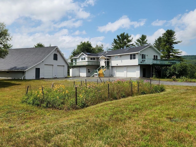 view of front of home with a wooden deck, a front lawn, and a garage