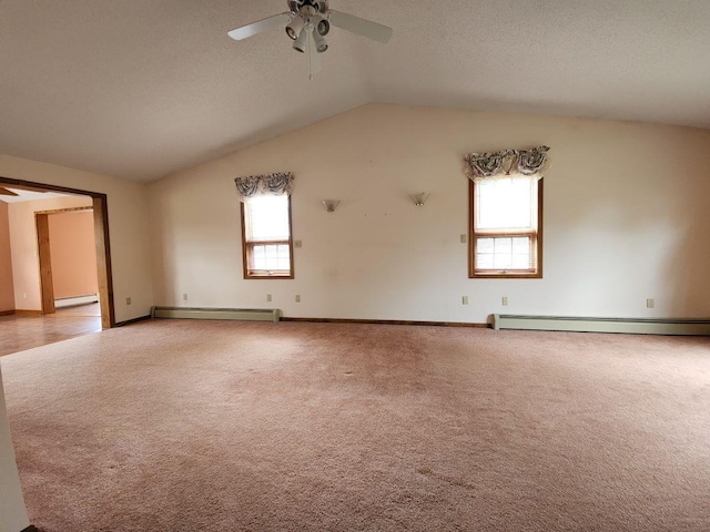 carpeted empty room featuring vaulted ceiling, a healthy amount of sunlight, and baseboard heating