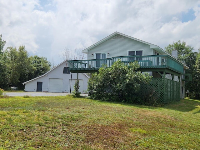 back of property featuring a deck, a garage, and a lawn