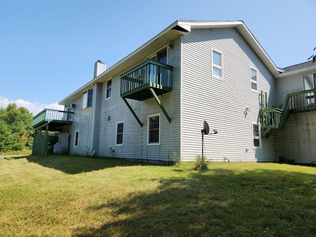 rear view of property featuring a yard and a balcony