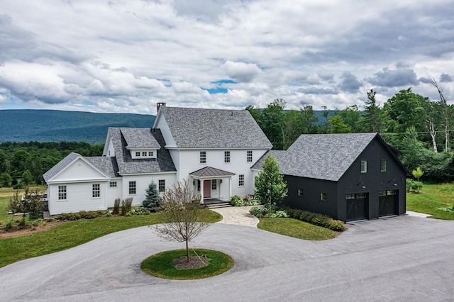 view of front facade featuring metal roof, a garage, a standing seam roof, roof with shingles, and curved driveway