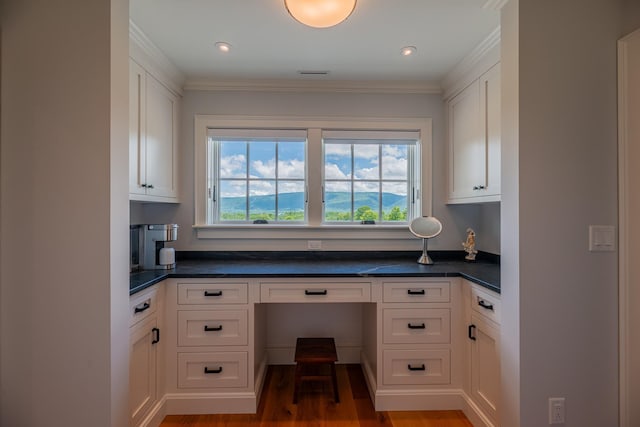 kitchen featuring dark countertops, built in desk, and white cabinets
