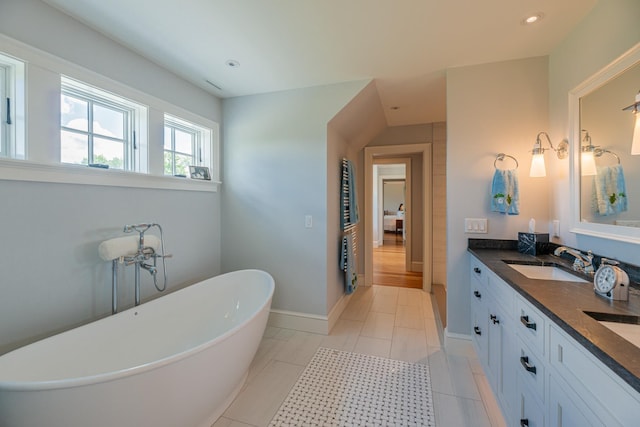 full bathroom featuring baseboards, double vanity, recessed lighting, a sink, and a freestanding bath