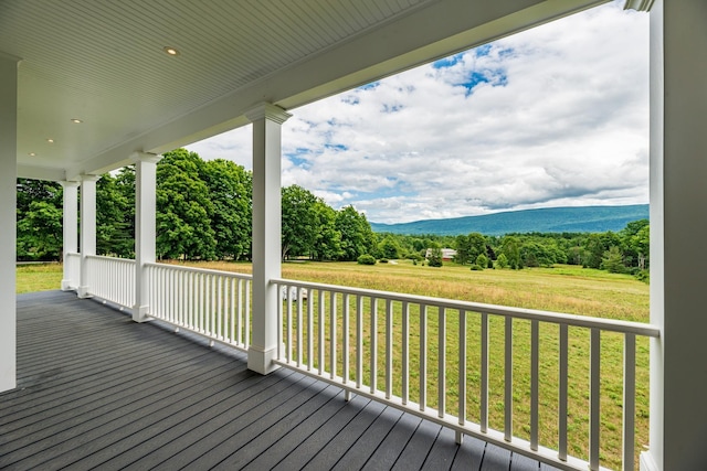 wooden terrace with a porch, a mountain view, and a lawn
