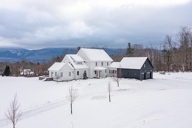 snow covered house featuring a mountain view and a chimney