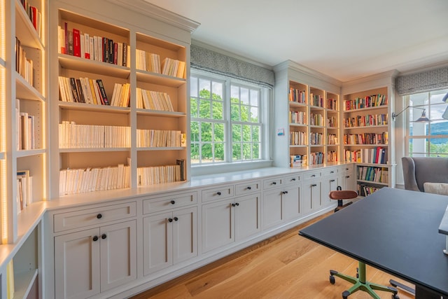 office space with light wood-style flooring and wall of books