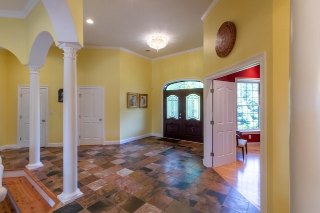 foyer featuring crown molding, a towering ceiling, and decorative columns