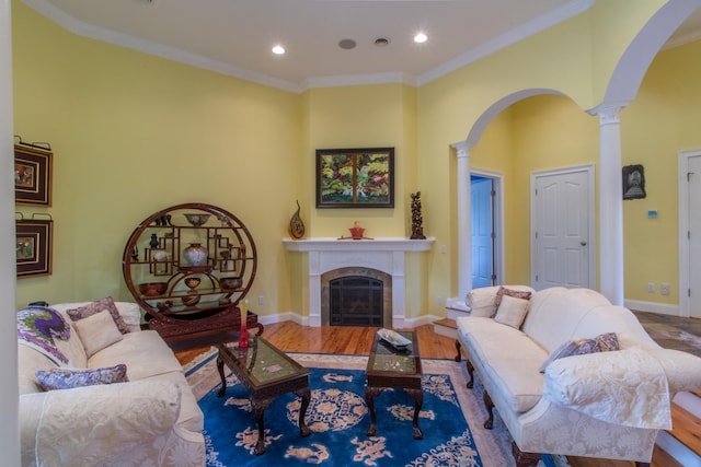 living room with crown molding, wood-type flooring, and decorative columns