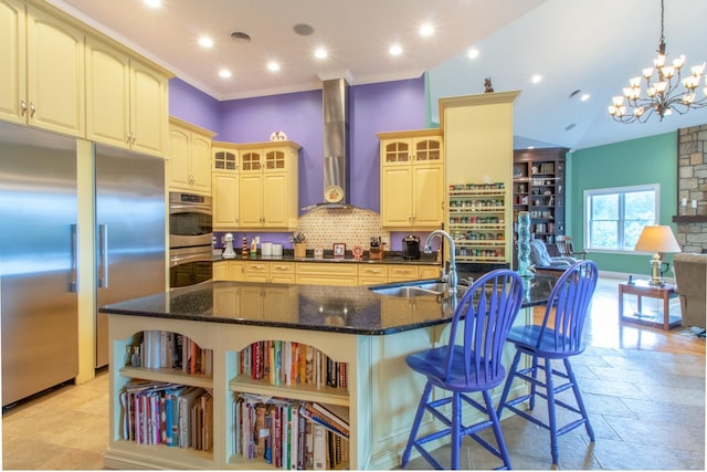 kitchen featuring wall chimney exhaust hood, stainless steel appliances, a large island, and sink