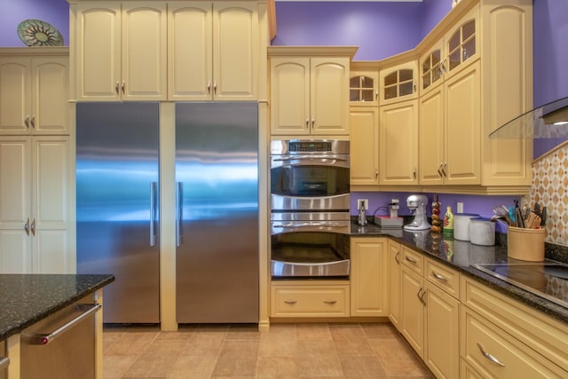 kitchen featuring stainless steel appliances, light tile patterned floors, and dark stone counters