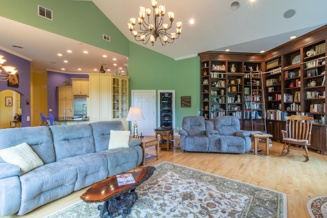 living room featuring ornamental molding, an inviting chandelier, and light hardwood / wood-style flooring