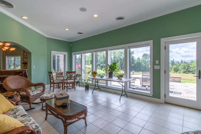 tiled living room with ornamental molding, a wealth of natural light, and a chandelier