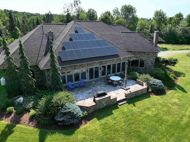 back of house featuring a lawn, a patio, and solar panels