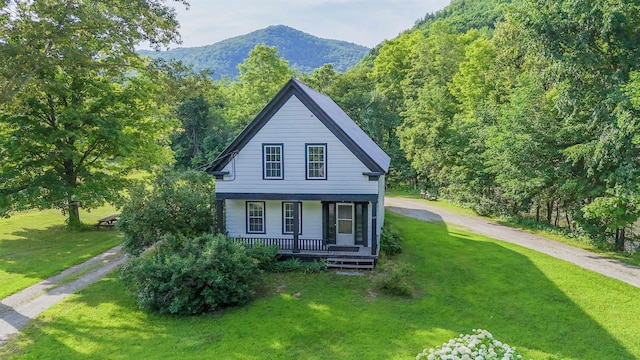 view of front of property with a mountain view, covered porch, and a front lawn