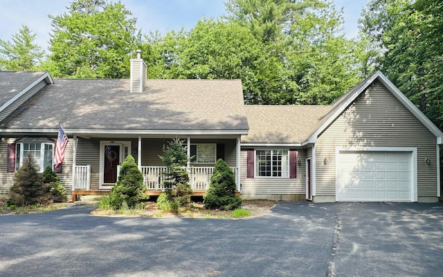 view of front of house with aphalt driveway, roof with shingles, a chimney, covered porch, and a garage