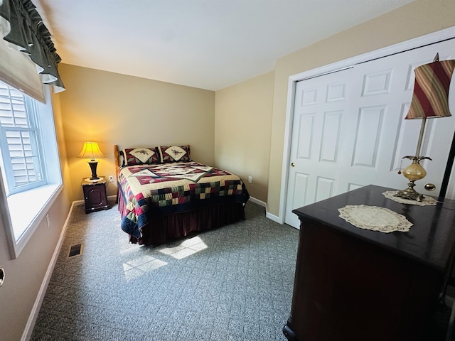 carpeted bedroom with a closet, visible vents, and baseboards