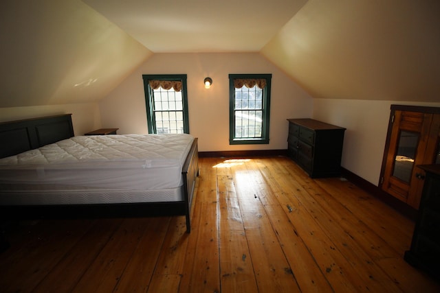 bedroom featuring vaulted ceiling, baseboards, and light wood-type flooring