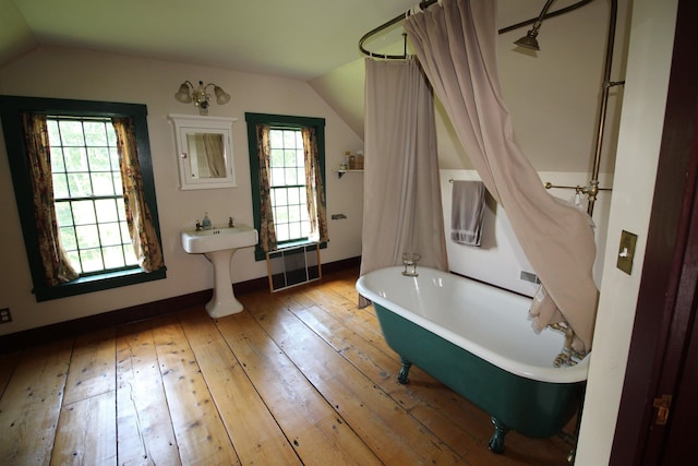 full bath with a sink, lofted ceiling, hardwood / wood-style floors, and a freestanding tub
