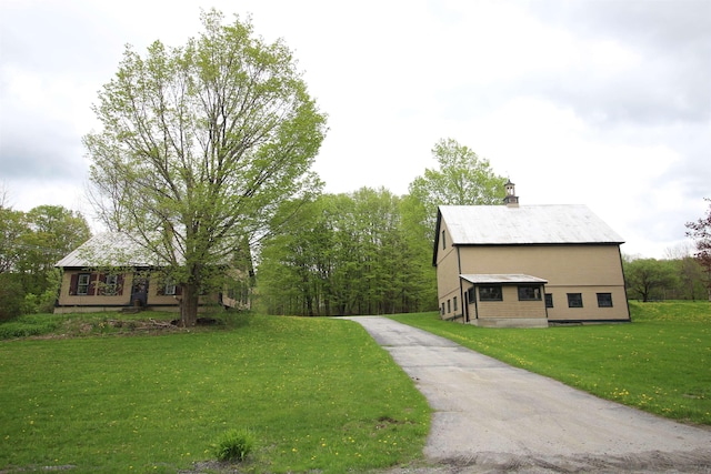 exterior space featuring a front lawn, a chimney, and driveway