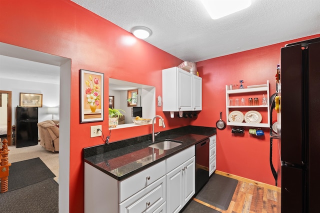 kitchen featuring sink, white cabinetry, hardwood / wood-style floors, black appliances, and a textured ceiling