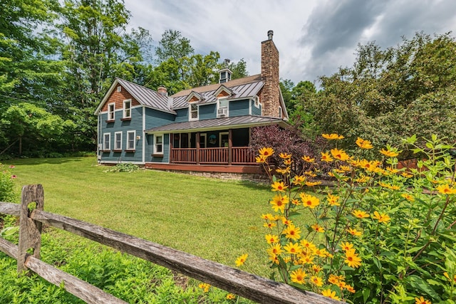 view of front facade featuring a chimney, metal roof, a standing seam roof, and a front yard