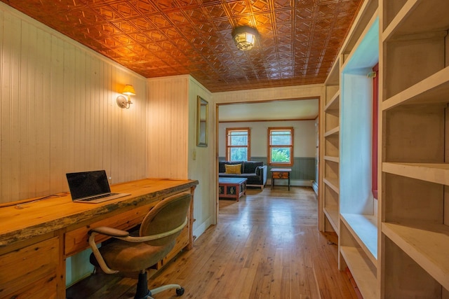 office space with wooden walls, an ornate ceiling, wood-type flooring, ornamental molding, and built in desk