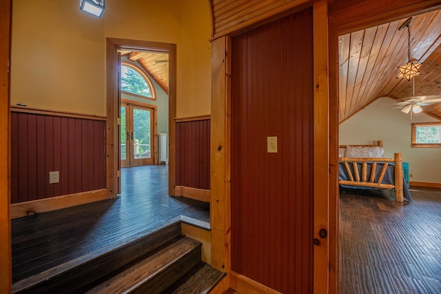 hallway featuring lofted ceiling, wainscoting, dark wood finished floors, and wood ceiling