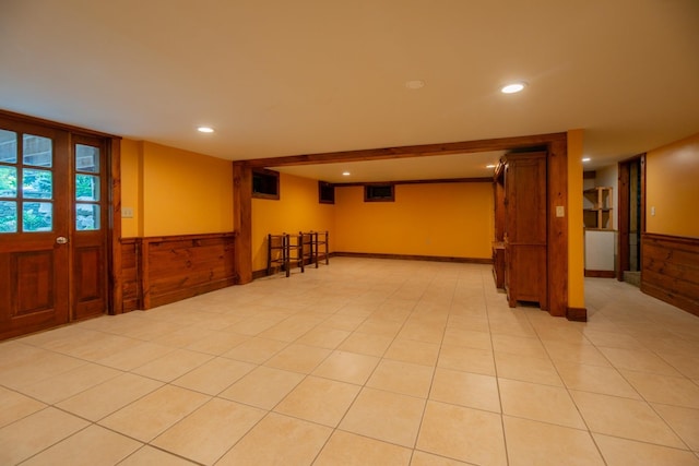 basement featuring wainscoting, wooden walls, light tile patterned floors, and recessed lighting