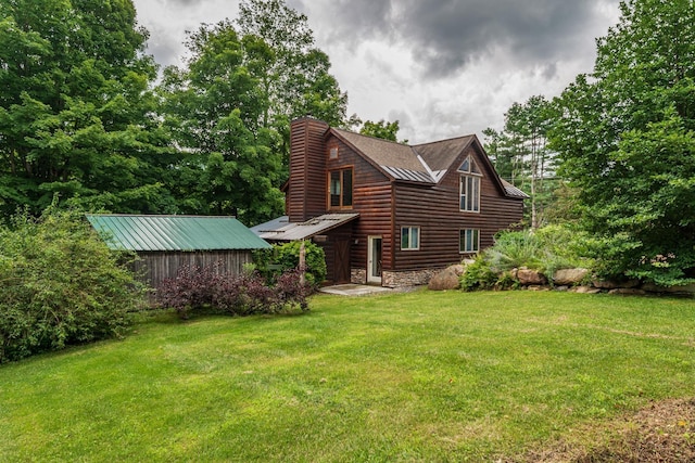 exterior space featuring stone siding, log veneer siding, metal roof, and a yard