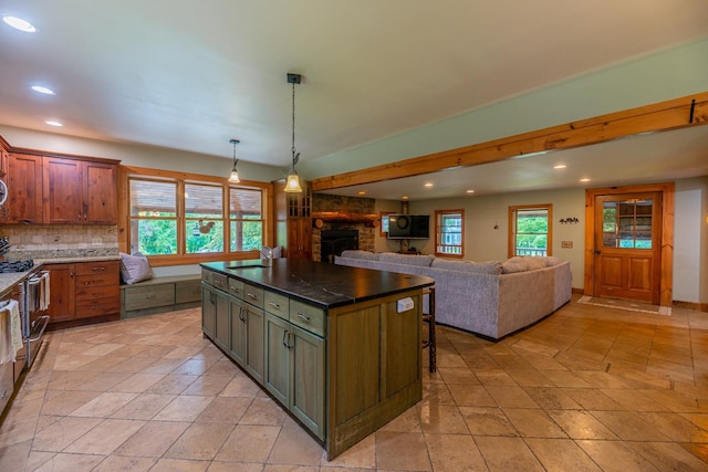 kitchen featuring dark countertops, a kitchen island, a breakfast bar area, stainless steel range with gas cooktop, and a sink