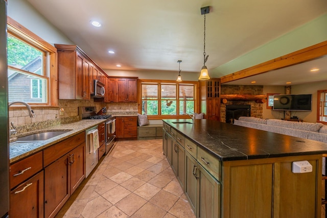 kitchen with stainless steel appliances, a center island, a sink, and hanging light fixtures