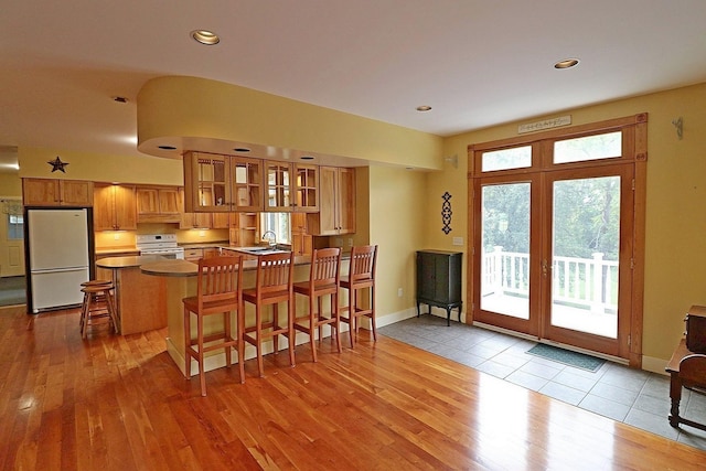 kitchen with sink, a breakfast bar area, range, white refrigerator, and kitchen peninsula