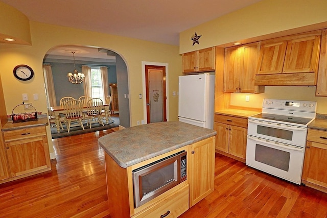 kitchen with an inviting chandelier, a center island, dark hardwood / wood-style flooring, pendant lighting, and white appliances