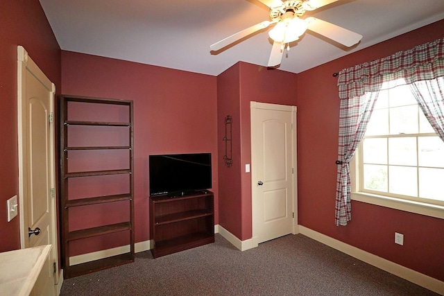 unfurnished bedroom with ceiling fan, dark carpet, and multiple windows