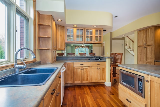 kitchen featuring stainless steel microwave, a sink, a peninsula, open shelves, and dark wood-type flooring