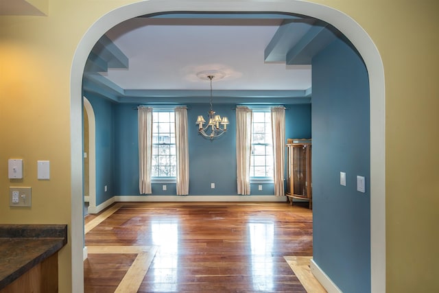 unfurnished dining area featuring healthy amount of natural light, wood finished floors, and arched walkways