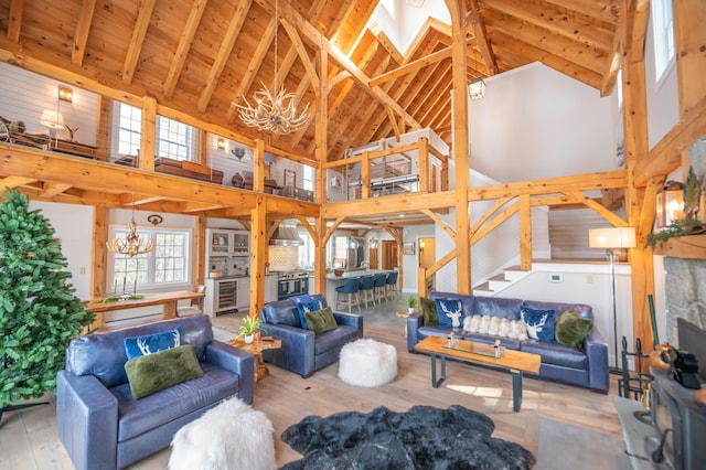 living room with a skylight, high vaulted ceiling, a notable chandelier, beam ceiling, and hardwood / wood-style floors