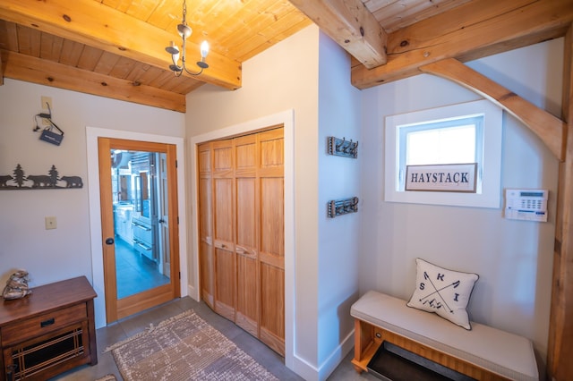 entryway with beamed ceiling, wooden ceiling, concrete floors, and an inviting chandelier