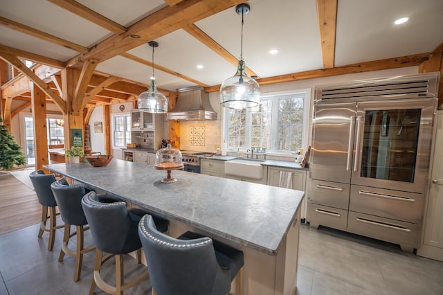 kitchen featuring hanging light fixtures, sink, custom range hood, and a kitchen bar