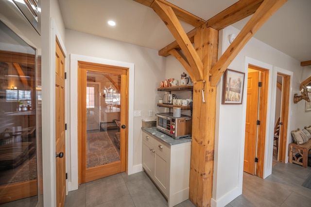 interior space featuring white cabinetry, beam ceiling, and beverage cooler