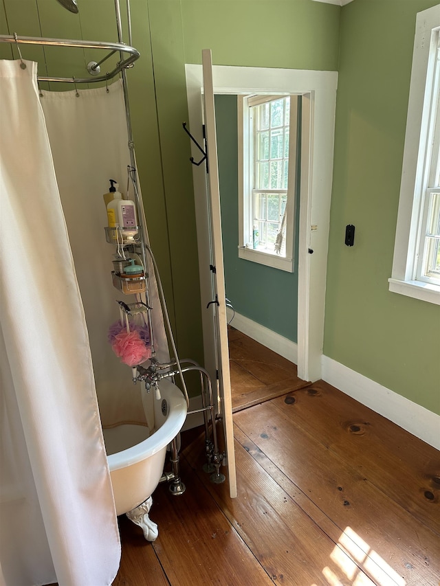 bathroom featuring a wealth of natural light, wood-type flooring, shower / tub combo, and toilet