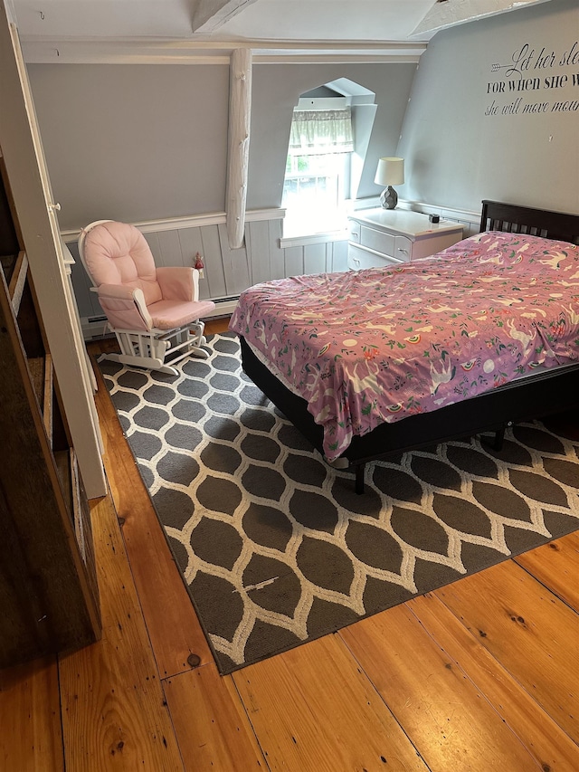 bedroom with baseboard heating and hardwood / wood-style floors