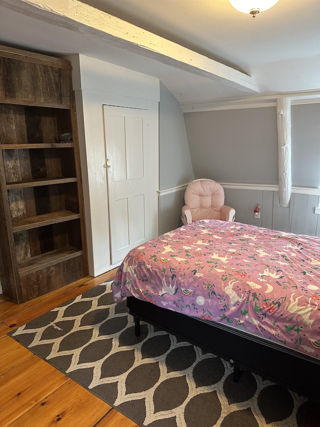 bedroom with wooden walls, a closet, and hardwood / wood-style flooring