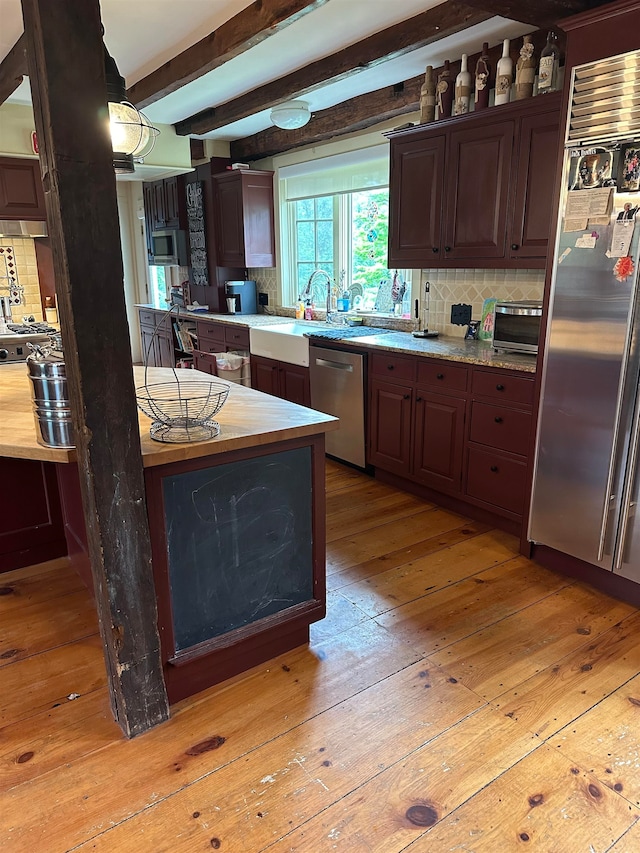 kitchen with beamed ceiling, light hardwood / wood-style flooring, stainless steel appliances, and tasteful backsplash