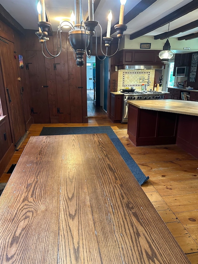 kitchen with light wood-type flooring, beam ceiling, an inviting chandelier, decorative light fixtures, and dark brown cabinetry