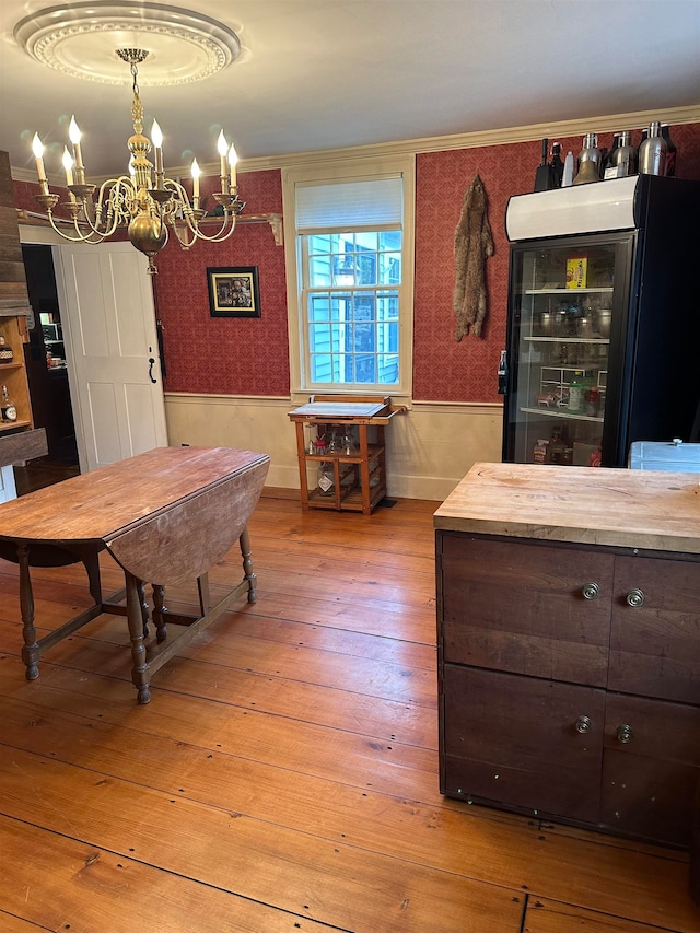 dining area featuring wine cooler, light hardwood / wood-style flooring, crown molding, and a notable chandelier